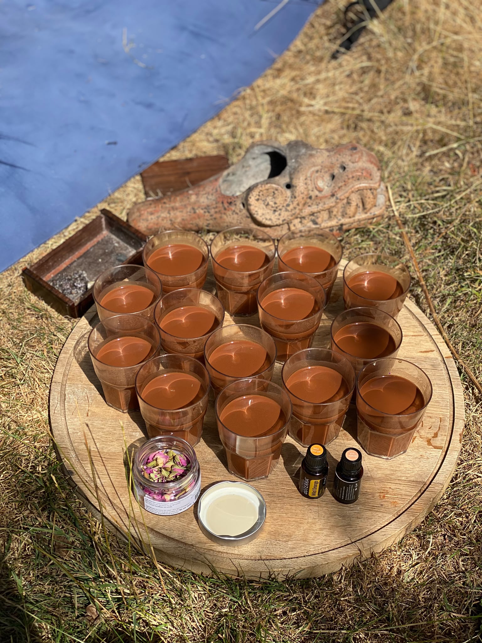 Glasses of cacao on a round wooden tray, with flowers and terracotta, outside in the sunshine
